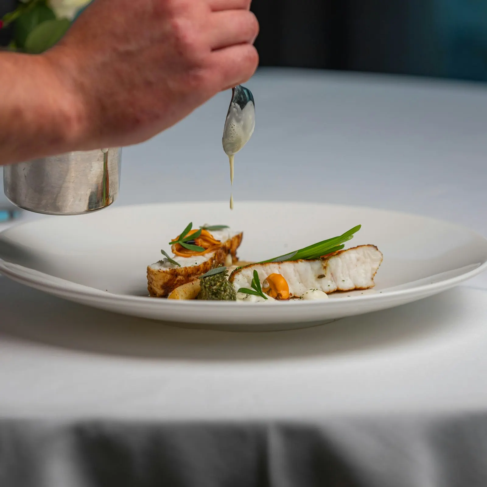 A chef finishing a plated course.